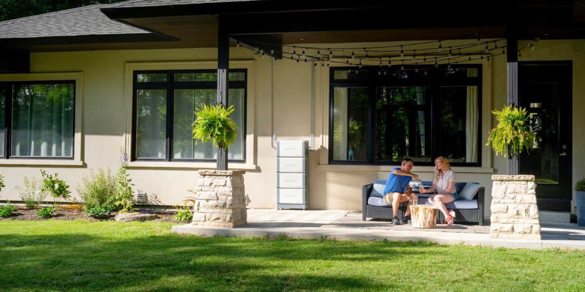 Modern home patio with couple sitting on outdoor sofa under covered pergola with hanging plants