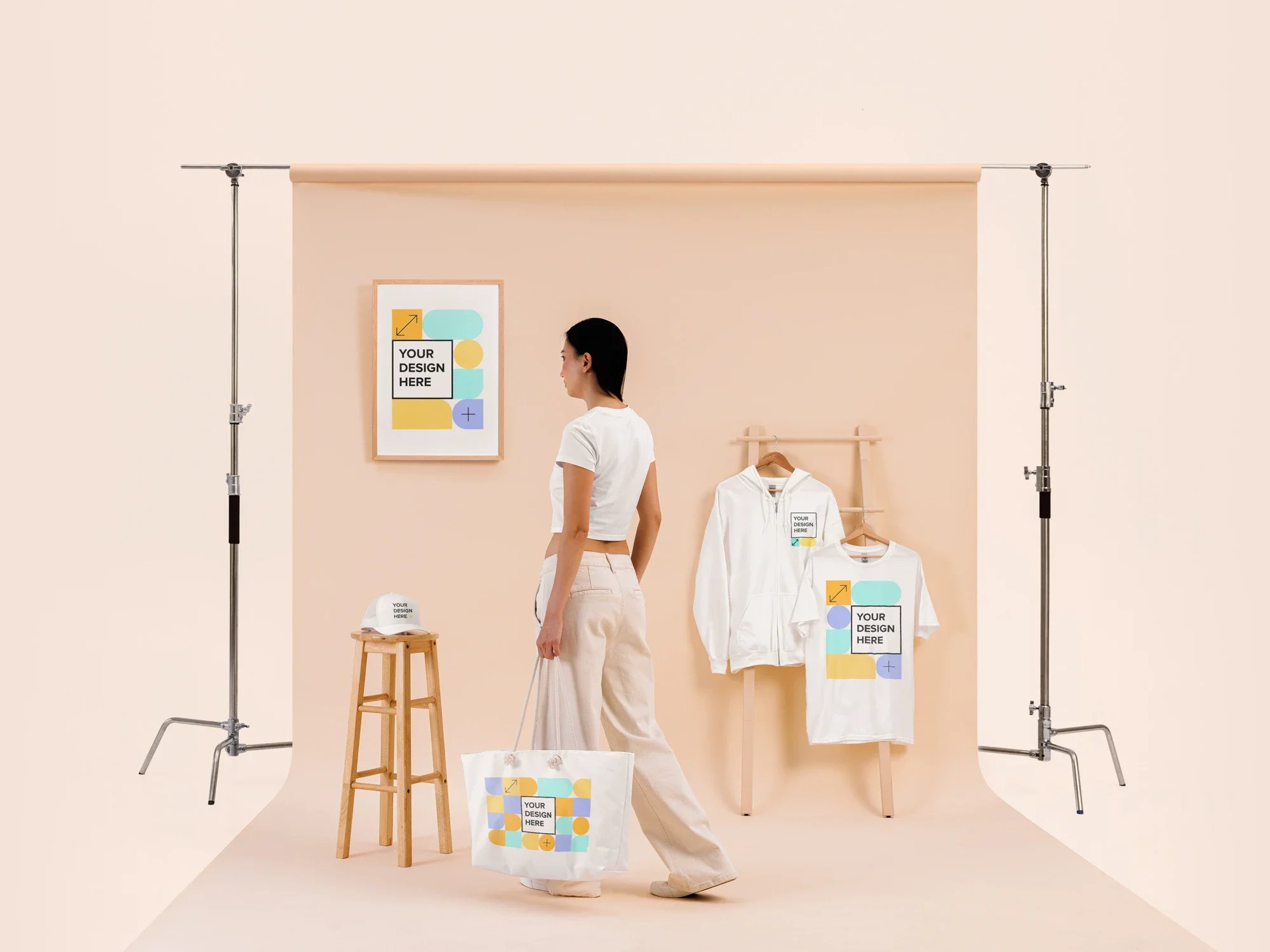 Mujer de perfil vistiendo ropa blanca personalizada junto a cartel enmarcado, bolsa y perchero en fondo beige claro