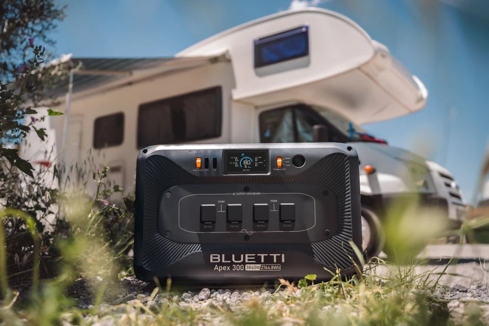 Portable power station with multiple outlets displayed outdoors in front of RV campsite