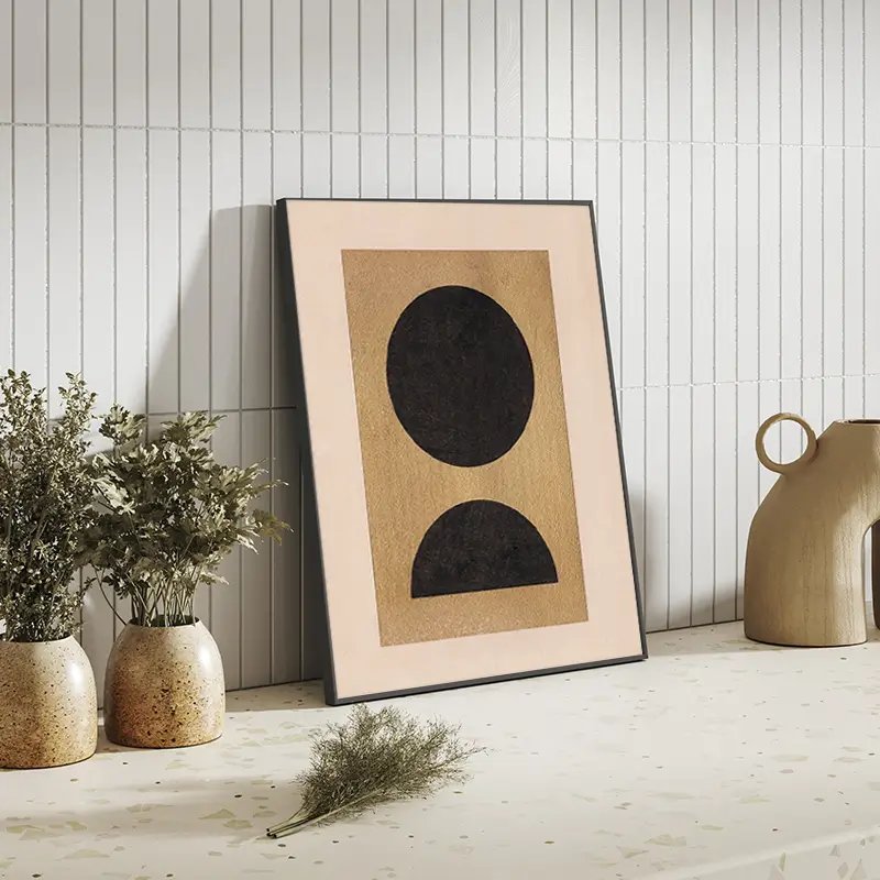 Abstrakte Kunstdruck in Schwarz und Gold neben Keramikvasen und Holzkrug auf weißem Fliesenboden