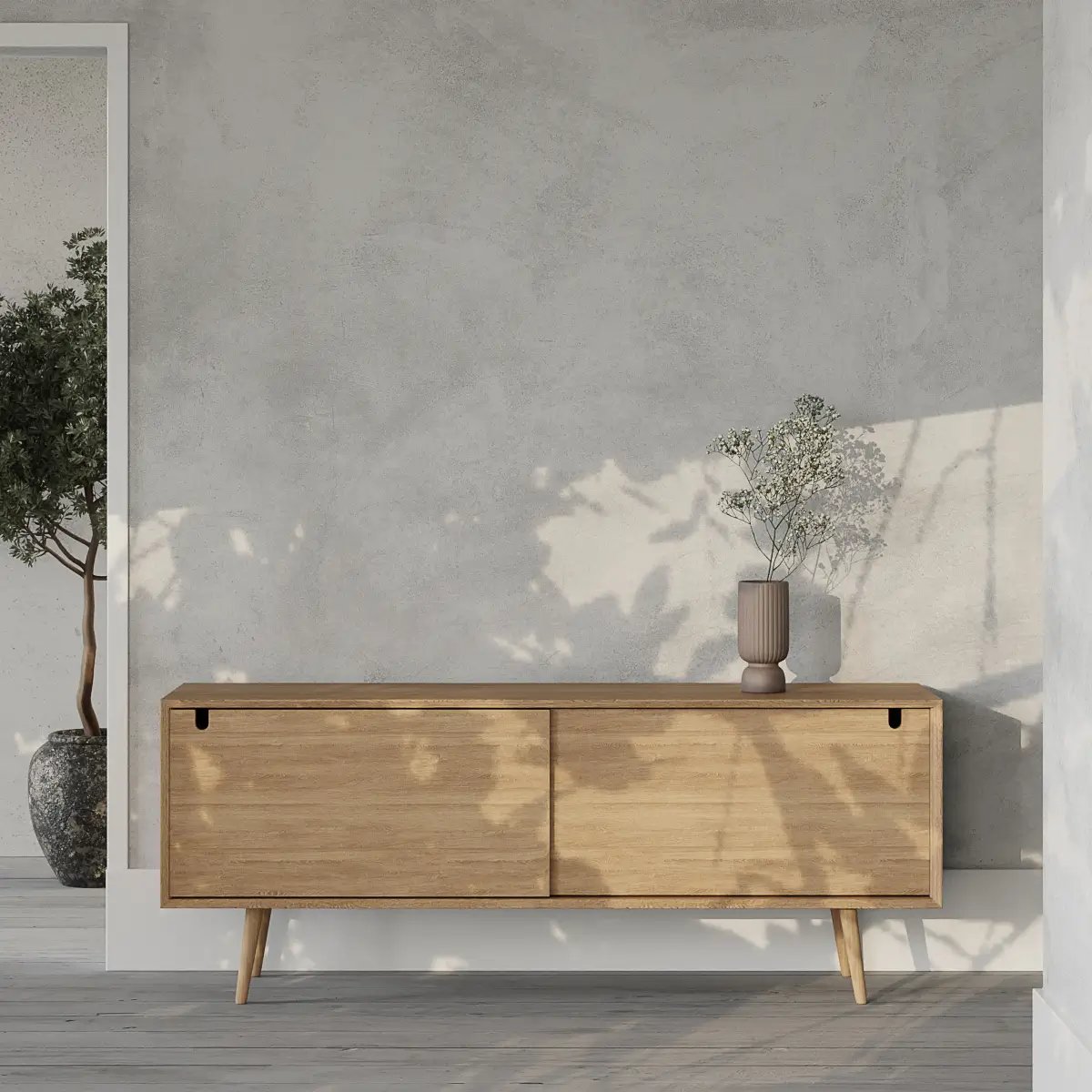 Helles Holzsideboard mit zwei Schubladen und spitzen Beinen vor grauer Betonwand mit Deko-Vase